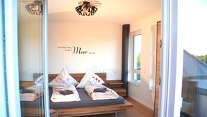 A modern bedroom with a bed, a decorative wall sign, and a view through a glass door. - * * * * * * Penthouse Meeresleuchten Duhner Entrée 19 (Cuxhaven)