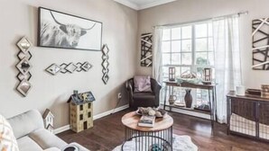 A living room with a sofa, a coffee table, a fireplace, and a window with curtains.