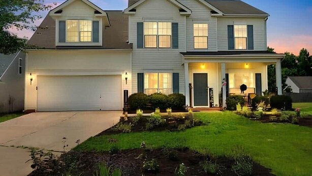 A two-story house with a garage, a covered front porch, and a well-maintained lawn.