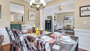 A dining area with a table set for four, chairs, a chandelier, and wall art.