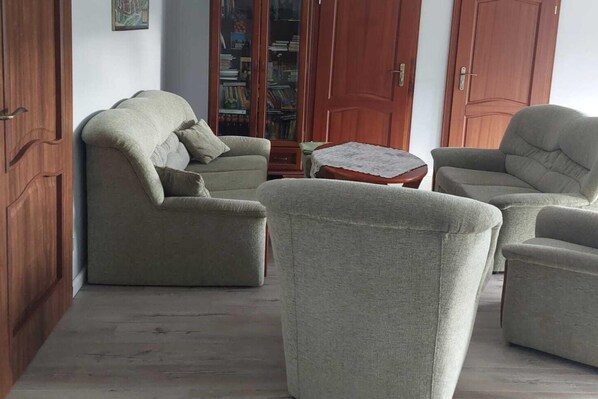 Una sala de estar con un sofá, sillones, una mesita de centro y una estantería.