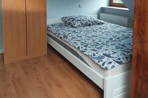 Un dormitorio con un armario de madera, una cama con ropa de cama estampada y un radiador blanco.