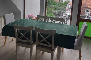 Une table à manger recouverte d’une nappe verte, avec des chaises blanches et un arrangement floral.