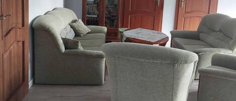 Una sala de estar con un sofá, sillones, una mesita de centro y una estantería.