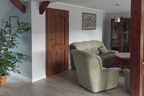 A room with a wooden door, a sofa, a map on the wall, and a potted plant.