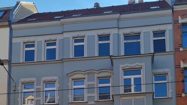 A multi-story building with a traditional architectural style, featuring a green door and a sign with text. - Apartment in Zwickau Near Horch Museum (Zwickau)