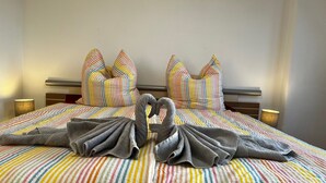 A hotel room with a bed featuring striped bedding, two pillows, and two towels arranged in a heart shape. - Apartment in Zwickau Near Horch Museum (Zwickau)