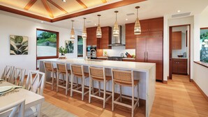 A modern kitchen with a central island, wooden cabinets, and hanging pendant lights.