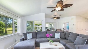 A modern living room with a grey sectional sofa, a white coffee table, and a ceiling fan.