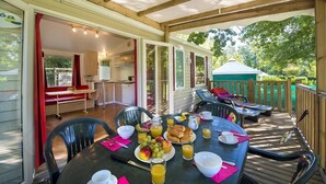 Un espace de restauration en plein air avec une table dressée pour le petit-déjeuner, comprenant des fruits, du pain et des boissons.