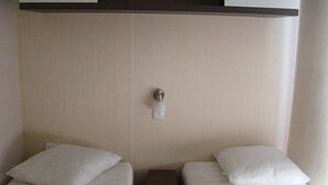 Une chambre d’hôtel avec deux lits simples, une petite table et une armoire avec un miroir.