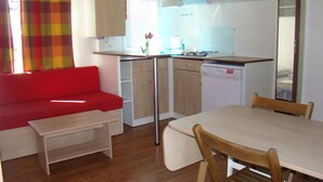 Une cuisine compacte avec un coin repas, un canapé rouge et une petite table.