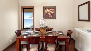 Un comedor con una mesa de madera dispuesta para seis personas, sillas, un jarrón con flores y un cuadro en la pared.