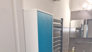 Une salle de bain avec une porte blanche, un meuble bleu, un miroir, un lavabo et un porte-serviettes.