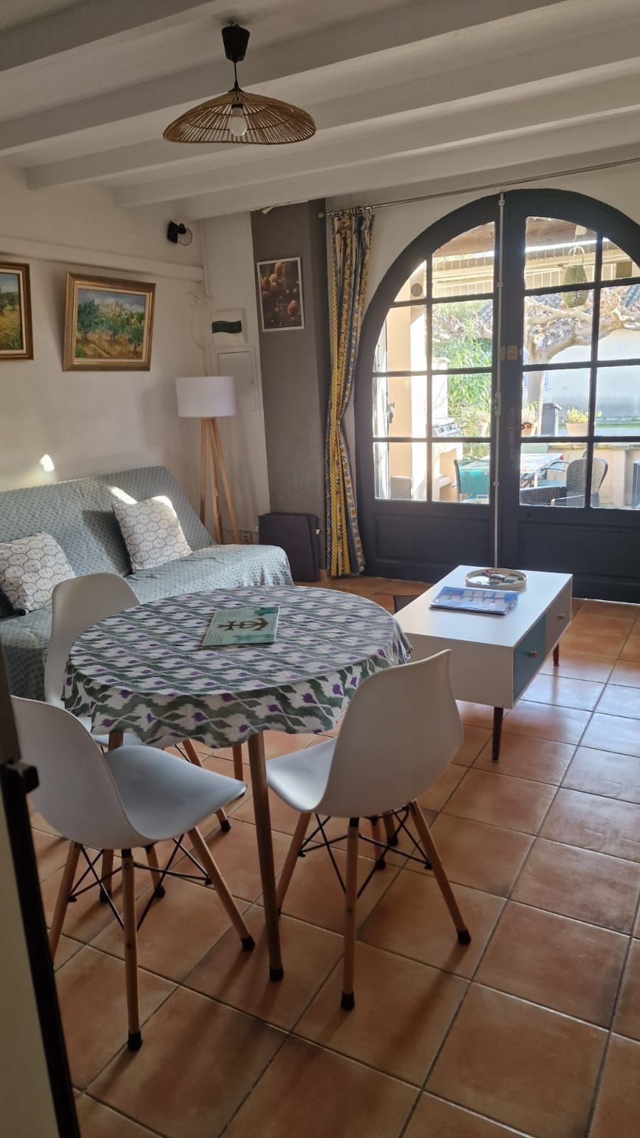Una habitación con cama, una mesa con sillas, una lámpara y vistas amplias por un ventanal.