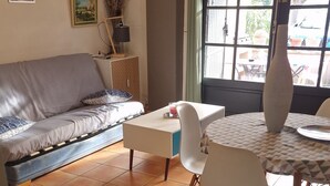 Un salon comprenant un canapé, une table à manger avec des chaises et une grande fenêtre donnant sur l’extérieur.