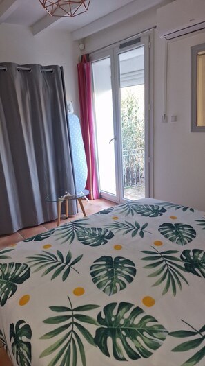 Un dormitorio con cama, una mesita, una ventana con cortinas y vistas al exterior.