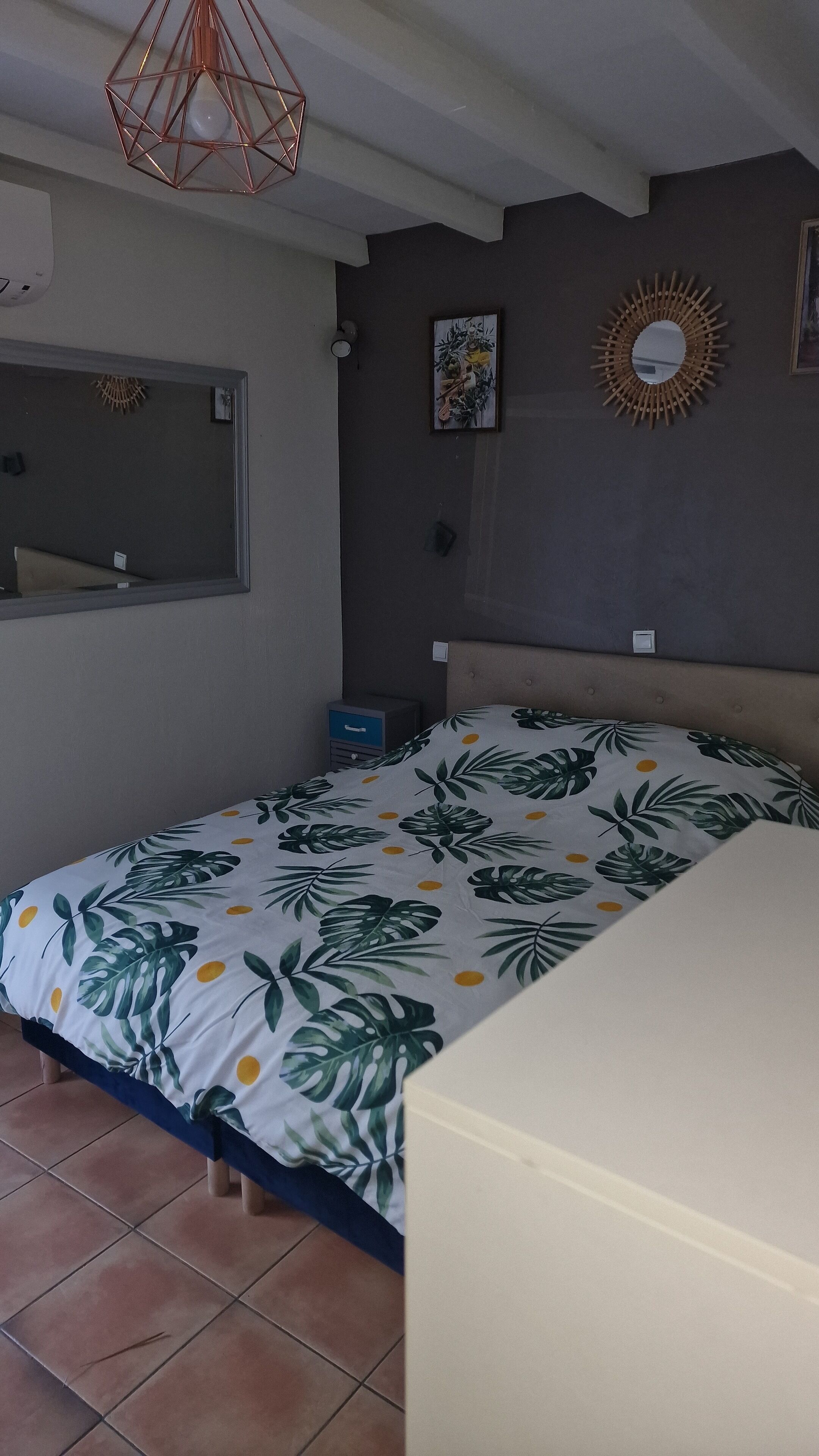 Une chambre à coucher comprenant un lit, une table de chevet, un miroir et un grand miroir décoratif fixé au mur.