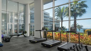 A gym with treadmills, a rowing machine, and dumbbells, with large windows overlooking a landscaped area. - Luxury apt in clifftop condo | Palace Ocean View (Funchal)