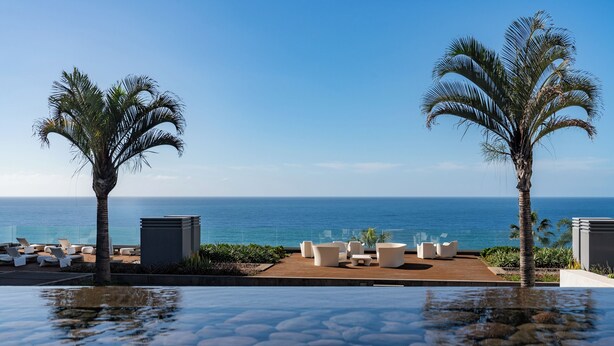 A poolside area with lounge chairs and a view of the ocean. - Luxury apt in clifftop condo | Palace Ocean View (Funchal)
