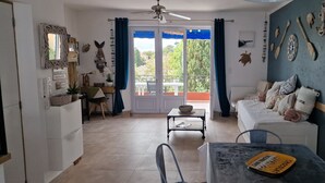 Une pièce comprenant un canapé, une table à manger et un balcon avec vue.