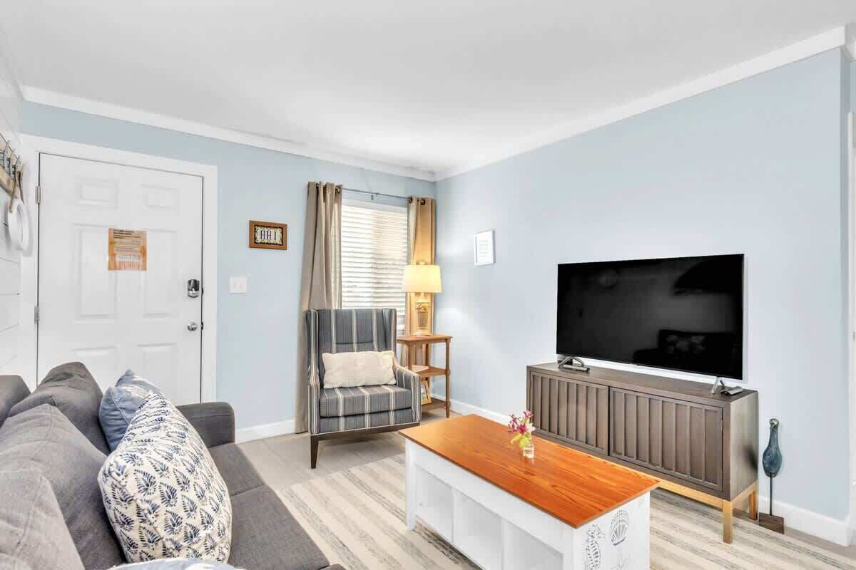 A living room with a sofa, armchair, coffee table, TV, and a cabinet.