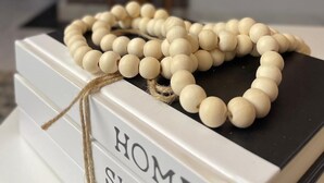 A white book with the word "HOME" on the cover, placed on a table with a string of white beads. - Charming 1-bedroom apartment in Naalya with a serene environment. (Kampala)