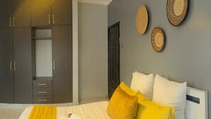 A bedroom with a bed, a wardrobe, and decorative wall art. - Charming 1-bedroom apartment in Naalya with a serene environment. (Kampala)