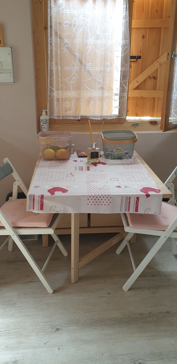 A dining table with a white tablecloth, two pink cushioned chairs, and a basket of lemons.