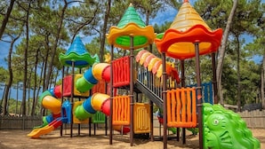 Un'area giochi con uno scivolo, strutture per arrampicata e una parete di arrampicata verde.