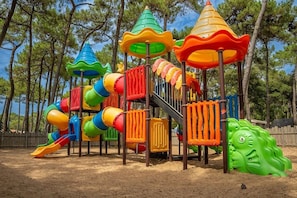 A playground with a slide, climbing structures, and a green climbing wall.