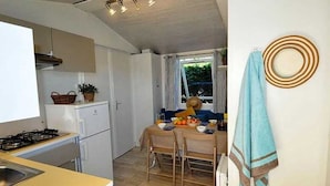 Una cocina compacta con estufa a gas, refrigerador y comedor con mesa para dos.