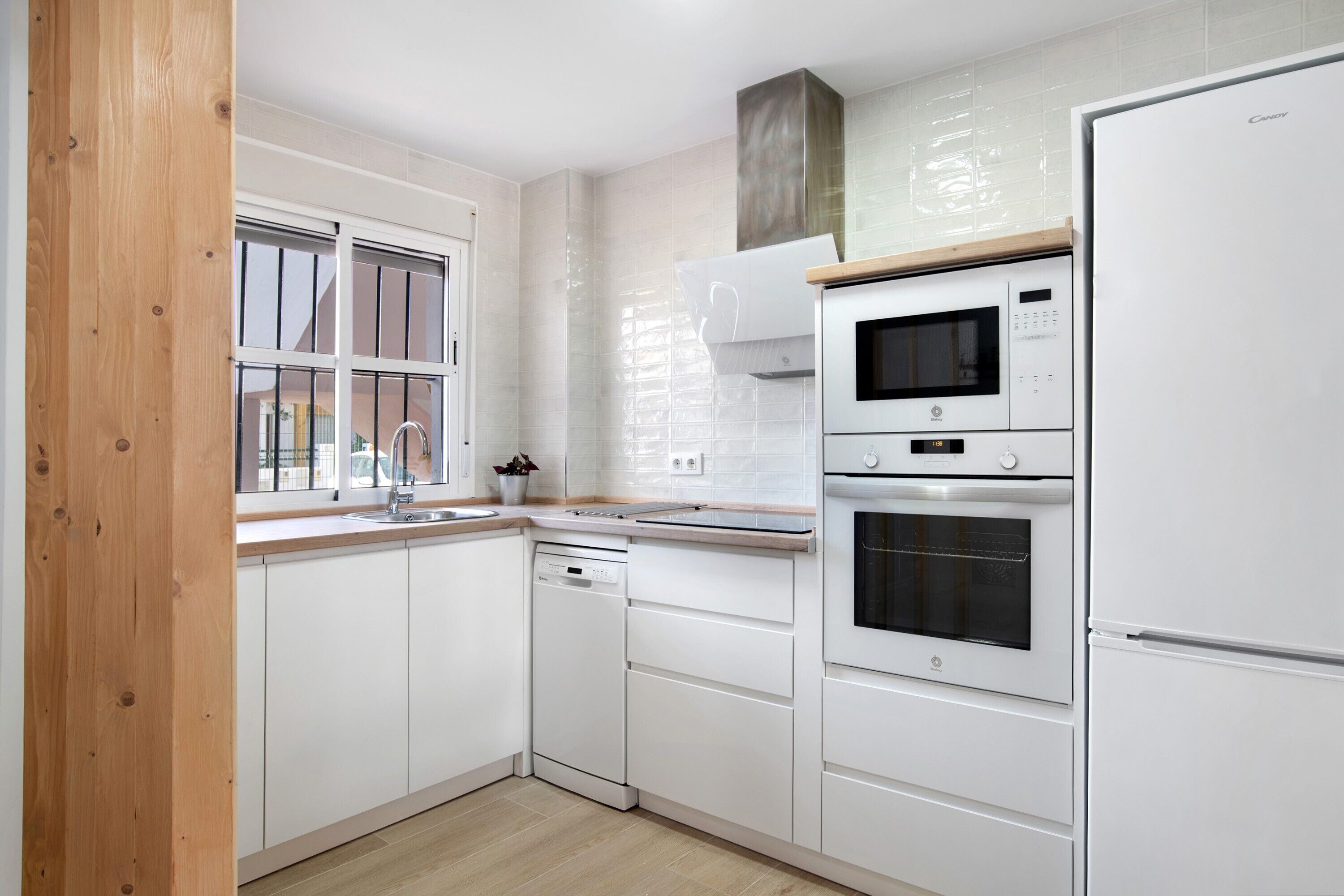 A modern kitchen with white cabinetry, a dishwasher, a double oven, and a refrigerator.