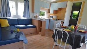 Un espacio habitable pequeño con sofá, mesa de comedor y kitchenette.