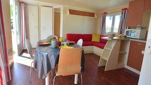 A compact living space with a dining area, a red sofa, and a kitchenette.
