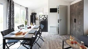 Une pièce moderne et bien éclairée, avec une table à manger, des chaises et une petite table d’appoint sur laquelle sont posées des boissons.