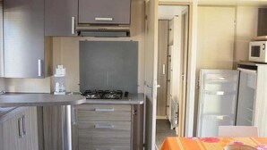 Eine kompakte Küche mit Gasherd, Mikrowelle und Kühlschrank.