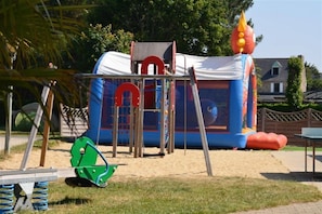 A children's play area with a slide, climbing net, and inflatable structures.