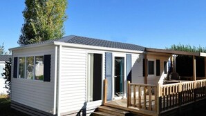 Ett litet, enplanshus på hjul med en träveranda och en inglasad veranda.