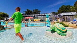 Ett poolområde med en stor skulptur av en sköldpadda och en person i en grön tröja som går förbi.
