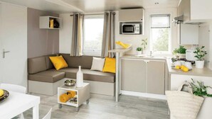 Una sala moderna con un sofá, una mesita y una zona de cocina con microondas y fregadero.
