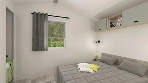 A bedroom with a bed, a window with curtains, a bedside table, and a shelf with books. - ZEcamping 4* animé piscine couverte dog friendly locatif TV BBQ 36m2 (Saint-Lunaire)