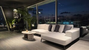 Un salon moderne avec un canapé d’angle blanc, une table basse ronde et un coin repas avec des chaises.