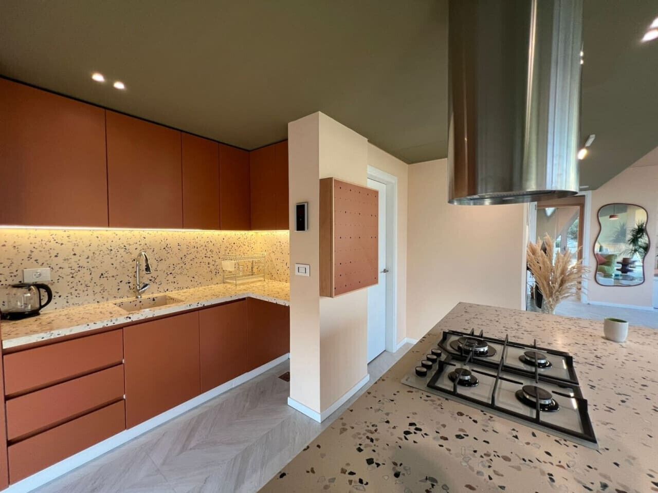 A modern kitchen with wooden cabinets, a granite countertop, and a stainless steel range hood.