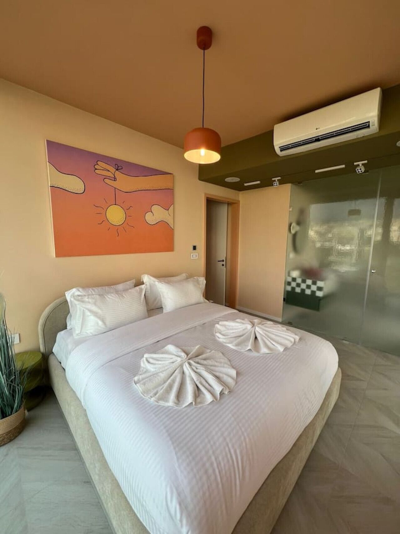 Une chambre d’hôtel avec un lit, un tableau, un climatiseur et une porte.