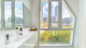 Une salle de bain moderne avec une grande fenêtre, un lavabo blanc et un miroir.