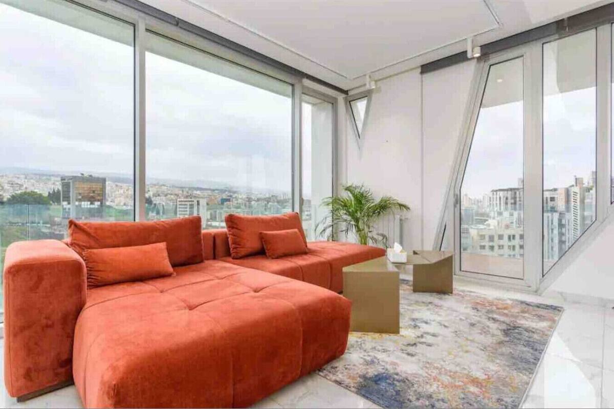 A modern living room with a sectional sofa, large windows, and a city view.