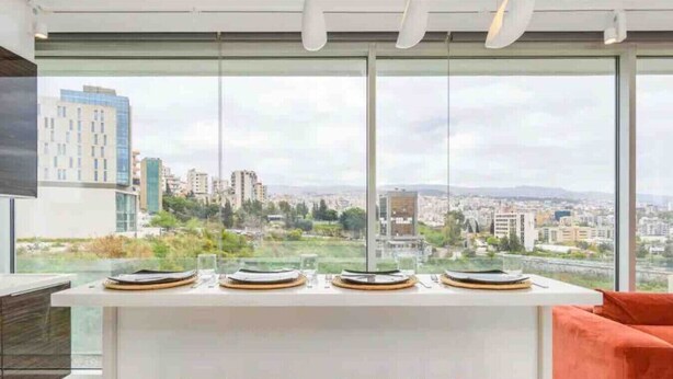 Une cuisine moderne dotée d’une grande fenêtre donnant sur un paysage urbain.