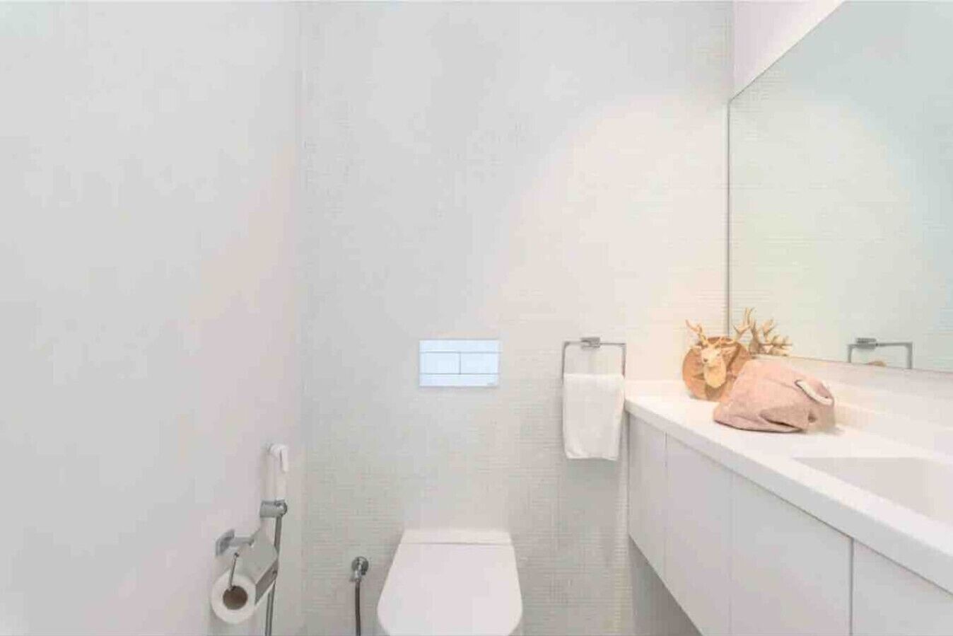 Et moderne badeværelse med toilet, vask og spejl.
