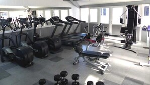 Ein Fitnessraum mit Laufbändern, Crosstrainern, einer Hantelbank und Kurzhanteln.